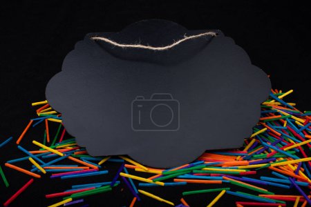 Photo for Black speech bubble shaped notice board  on colorful sticks on black - Royalty Free Image