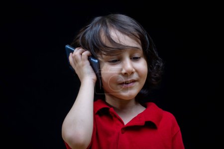Téléchargez les photos : Petit garçon tenir smartphone comme gadget de communication mobile moderne - en image libre de droit