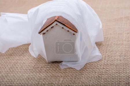 Foto de Pequeña casa modelo envuelta en papel sobre un fondo marrón - Imagen libre de derechos