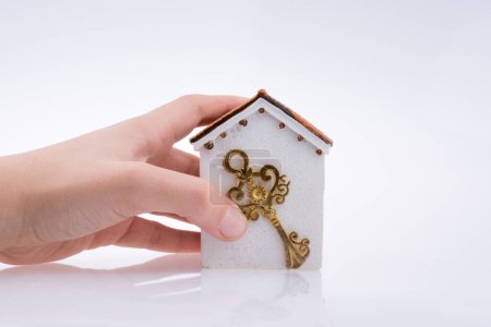 Foto de Mano sosteniendo una llave dorada cerca de una casa sobre un fondo blanco - Imagen libre de derechos