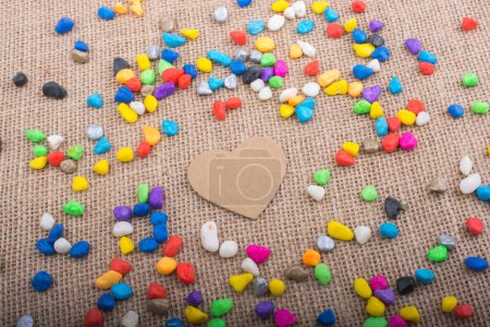 Photo for Paper heart amid colorful pebbles on canvas ground - Royalty Free Image