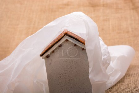 Foto de Pequeña casa modelo envuelta en papel sobre un fondo marrón - Imagen libre de derechos