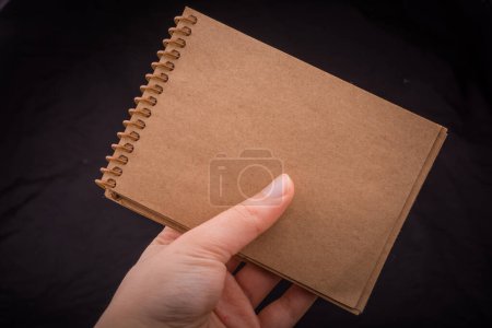 Foto de Cuaderno blanco en mano sobre fondo de color negro - Imagen libre de derechos