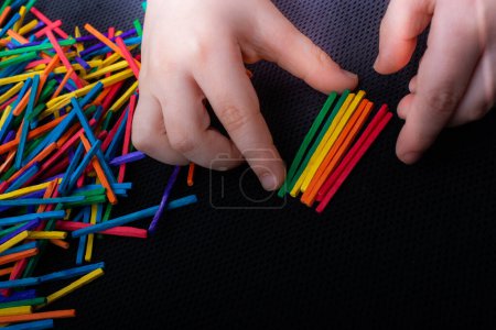 Téléchargez les photos : Enfant jouant avec des bâtons en bois colorés pour la créativité sur fond blanc - en image libre de droit