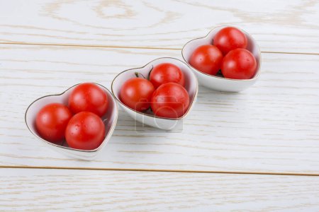 Foto de Tomates cherry rojos maduros en tazón en forma de corazón - Imagen libre de derechos