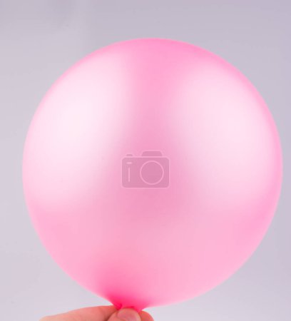 Photo for Hand holding a pink balloon on a white background - Royalty Free Image