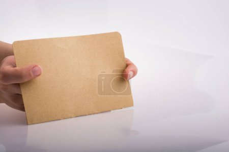 Foto de Mano sosteniendo una hoja de papel sobre un fondo blanco - Imagen libre de derechos