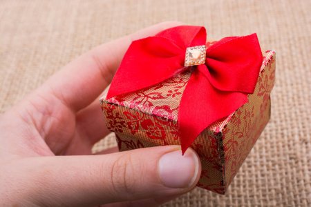 Foto de Caja de regalo con cinta roja hecha de cartón en mano - Imagen libre de derechos