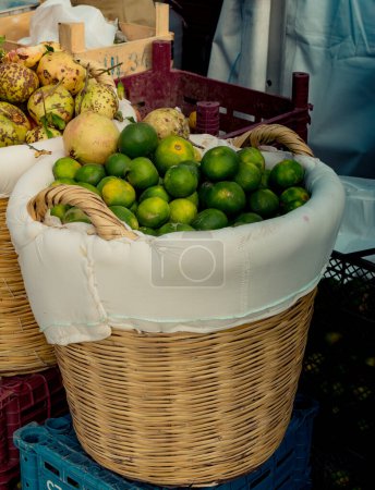 Téléchargez les photos : Mandarines vertes dans un panier de paille dans la vue - en image libre de droit