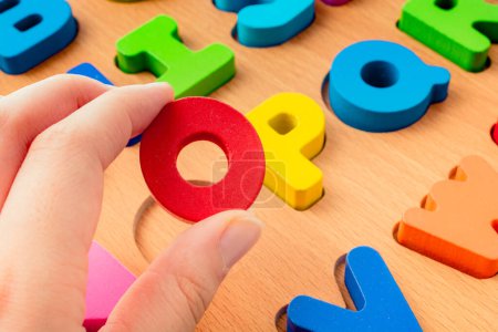 Photo for Colorful Letter of Alphabet O made of wood in hand - Royalty Free Image