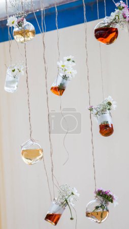 Téléchargez les photos : Bouteilles de tisane avec des fleurs suspendues à des cordes - en image libre de droit