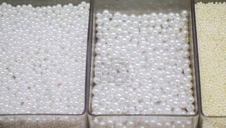 Foto de Cuentas de perlas que se encuentran en diferentes cajas como material para joyas hechas a mano - Imagen libre de derechos