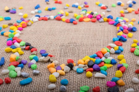 Colorful little pebbles form a heart shape on canvas ground