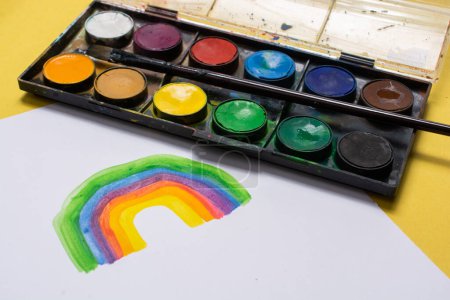 Foto de Niños pintando a mano arco iris con pincel durante la cuarentena del coronavirus en casa. - Imagen libre de derechos