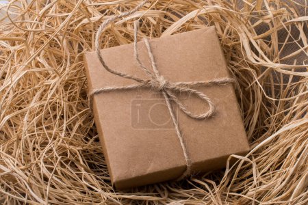Foto de Caja de regalo de color marrón sobre un fondo lleno de paja - Imagen libre de derechos