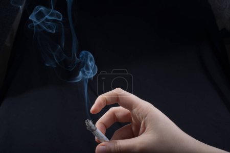 Téléchargez les photos : Main tient la cigarette fumante avec de la fumée autour - en image libre de droit