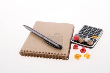 Foto de Calculadora, papel arrugado y bolígrafo en espiral sobre fondo blanco - Imagen libre de derechos