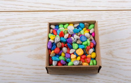 Téléchargez les photos : Petits cailloux colorés dans une boîte sur texture en bois - en image libre de droit