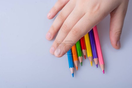 Téléchargez les photos : Crayons de couleur à main placés sur un fond blanc - en image libre de droit