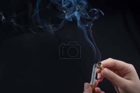 Téléchargez les photos : Main tient la cigarette fumante avec de la fumée autour - en image libre de droit
