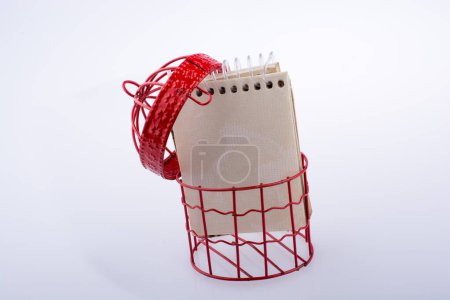 Téléchargez les photos : Petit carnet placé dans une maison d'oiseaux de couleur rouge avec des barres métalliques - en image libre de droit