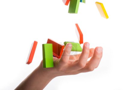 Téléchargez les photos : Tomber domino coloré sur une main - en image libre de droit