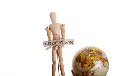 Téléchargez les photos : Homme en bois tenant signe d'éducation debout devant un globe sur un fond blanc - en image libre de droit
