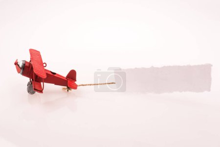 Téléchargez les photos : Jouet avion rouge avec bannière en papier sur fond blanc - en image libre de droit