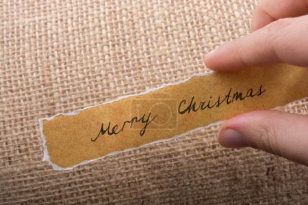 Foto de Feliz Navidad redacción escrita en un papel roto en la mano - Imagen libre de derechos
