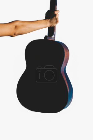 Photo for Young man rising an accoustic guitar in the blue sky - Royalty Free Image
