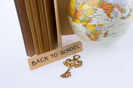 Téléchargez les photos : Globe, clé et titre de retour à l'école sur un carnet - en image libre de droit