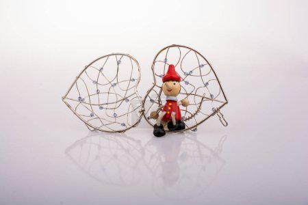 Téléchargez les photos : Poupée Pinocchio en bois assise sur une cage en forme de coeur - en image libre de droit