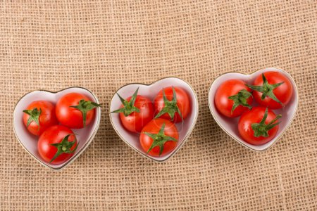 Téléchargez les photos : Tomates cerises rouges mûres dans un bol en forme de coeur - en image libre de droit