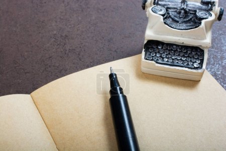 Foto de Pluma y máquina de escribir en el cuaderno sobre fondo de color marrón a la vista - Imagen libre de derechos
