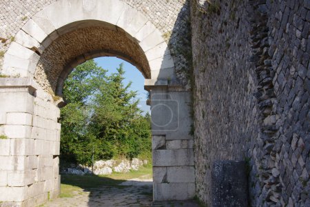 Site archéologique d'Altilia : Au premier plan une technique murale réticulée utilisée par l'Empire romain en arrière-plan l'une des quatre portes d'accès à la ville romaine. Sepino, Molise, Italie