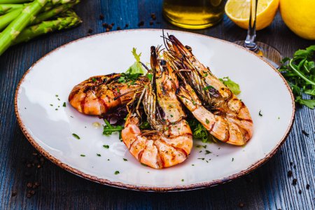 Photo for Grilled tiger prawns with greens on white plate - Royalty Free Image