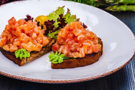 Photo for Healthy toasts with rye bread with salmon, avocado mousse, lettuce on white plate. - Royalty Free Image