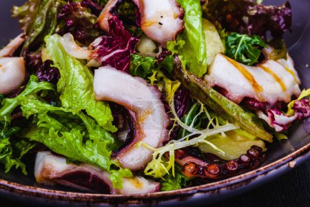 Téléchargez les photos : Salade de poulpe avec pommes de terre et légumes verts mélangés dans une assiette - en image libre de droit
