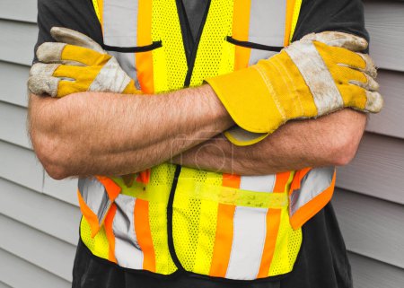 Photo for Man wearing safety vest and work gloves beside exterior siding. - Royalty Free Image