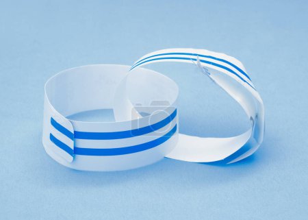 Discarded hospital wristbands on light blue