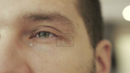 Upset man in despair and crying with tears in eye. Teardrop on his face. Drama, depression concept. Slow motion