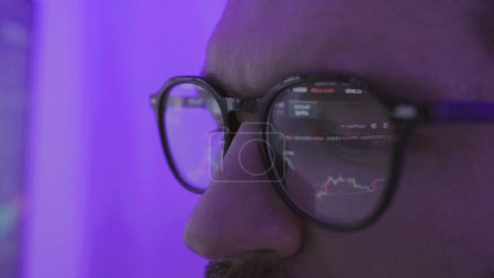 Serious businessman trader analyst in glasses looking at computer monitor. Slow motion. Stock market, trade, investment, technology concept. Close up