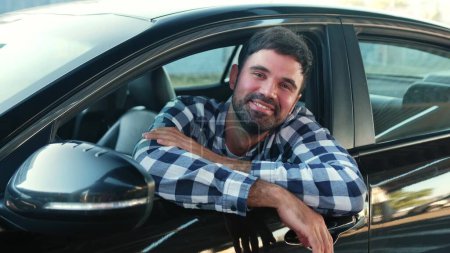 Lächelnder junger Mann, der im Auto sitzt, während er auf das offene Fenster in der Stadt blickt. Transport, Lebensstil, Personenkonzept