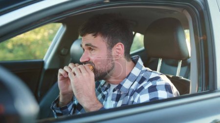Hungry male driver eating snack in the car. Transport, food, lifestyle, people concept