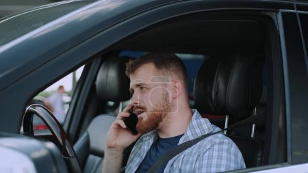 Hombre caucásico respondiendo a la llamada, usando el teléfono móvil en el coche. Transporte, tecnología, concepto de viaje. Movimiento lento