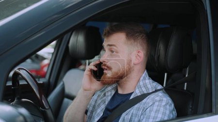 Hombre caucásico usando cinturón de seguridad en el coche, hablando por teléfono móvil. Transporte, tecnología, concepto de viaje. Movimiento lento