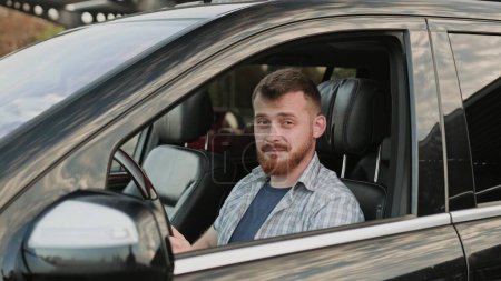 Conductor masculino mostrando gesto aceptable mientras está sentado en el coche y listo para conducir. Transporte, estilo de vida, concepto de viaje. Movimiento lento