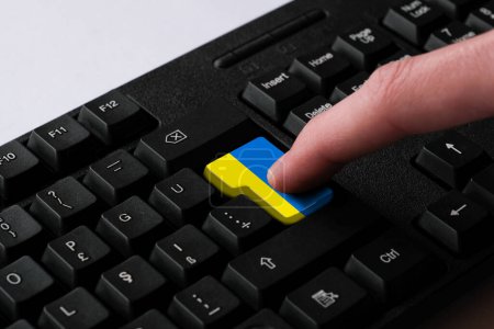 Photo for Pressing enter button with Ukraine flag, represents a cyber-attack of Ukraine, metaphor of learning Ukrainian language, black keyboard close up, front view, selective focus - Royalty Free Image