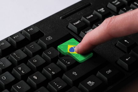 Téléchargez les photos : Appuyez sur le bouton Entrée avec le drapeau du Brésil, représente une cyber-attaque du Brésil, métaphore de l'apprentissage de la langue portugaise, clavier noir de près, vue de face, mise au point sélective - en image libre de droit