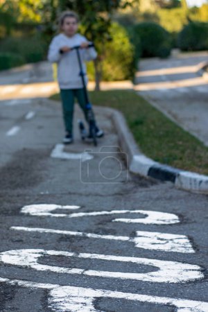 Téléchargez les photos : Arrêter le plaisir : Garçon sur scooter sous stop signe - en image libre de droit